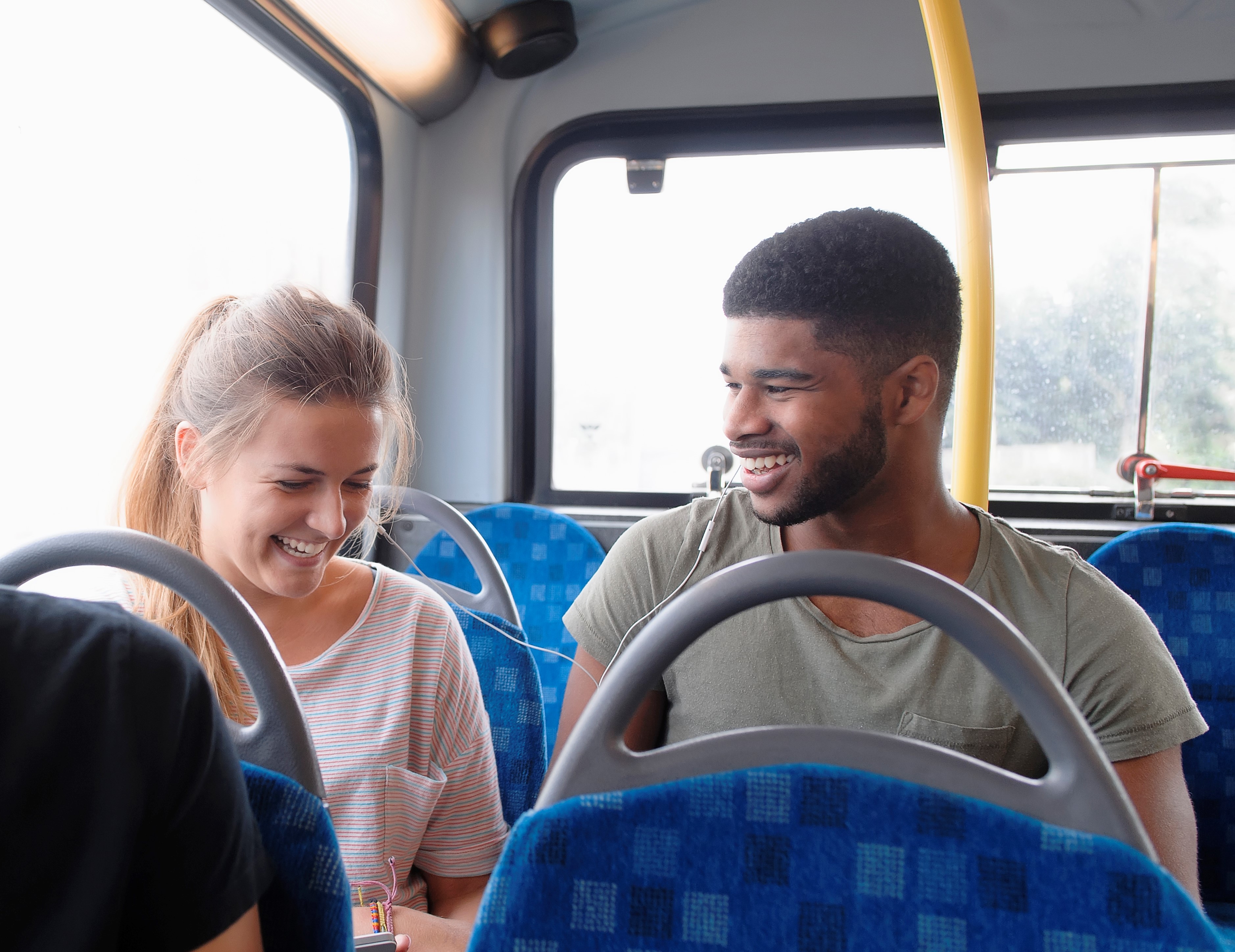 Een man en vrouw lachen samen terwijl ze naast elkaar in een bus van Arriva zitten.