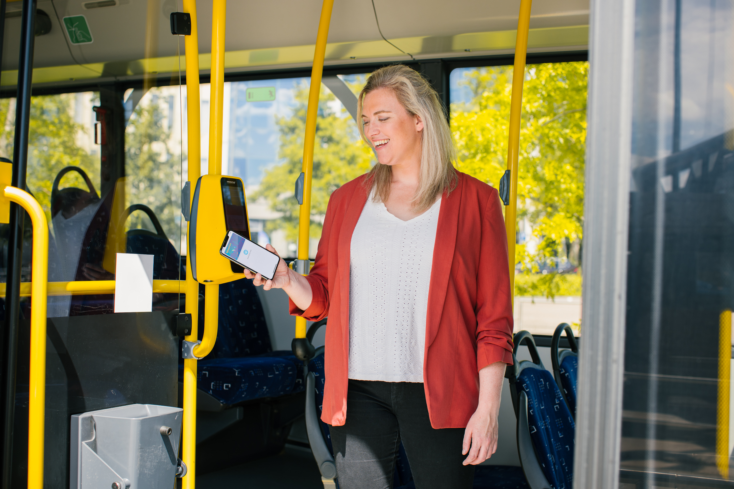 Een vrouw checkt uit van de bus met haar telefoon bij de OV-betaalpaal.